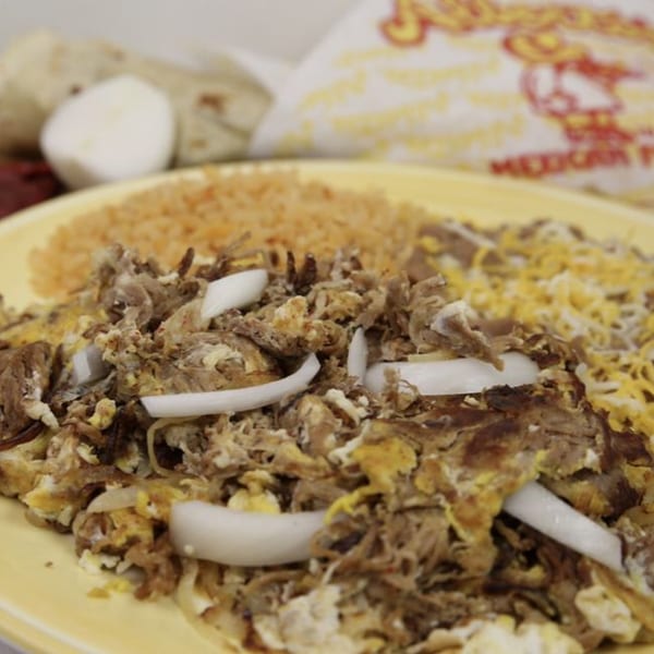 Alberto's Mexican Food carne asada with rice, beans, cheese, and onions on a yellow plate.