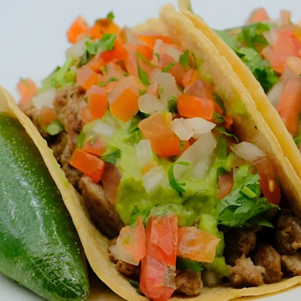 Three Alberto's Mexican Food tacos filled with meat, guacamole, pico de gallo, and a green pepper.