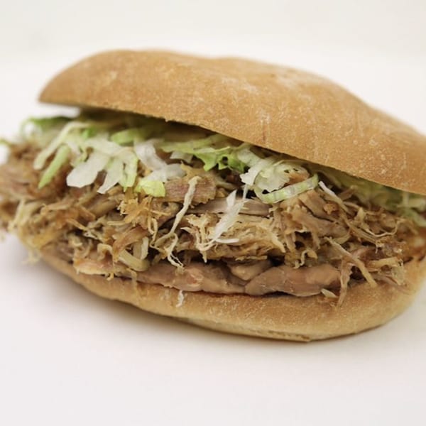 Alberto's Mexican Food's torta with shredded meat, beans, and lettuce on a white background.